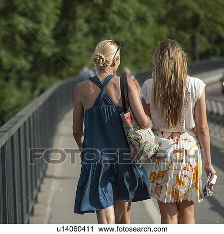Stock Image - Two female friends walking on a bridge, Stockholm, Sweden. Fotosearch