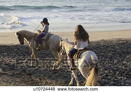Stock Photo - Two girls riding horses on the beach, Sayulita, Nayarit, Mexico. Fotosearch
