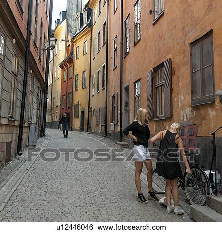 Stock Photograph - Two women with bicycle on a street, Gamla Stan, Stockholm, Sweden. Fotosearch