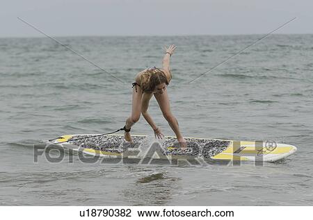 Stock Image - Woman falling from a surfboard in the sea, Sayulita, Nayarit, Mexico. Fotosearch