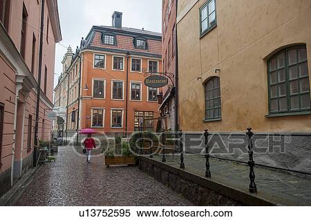 Woman holding an umbrella in rain on a street, Uppsala, Sweden View Large Photo Image Stock Photography - Woman holding an umbrella in rain on a street, Uppsala, Sweden. Fotosearch