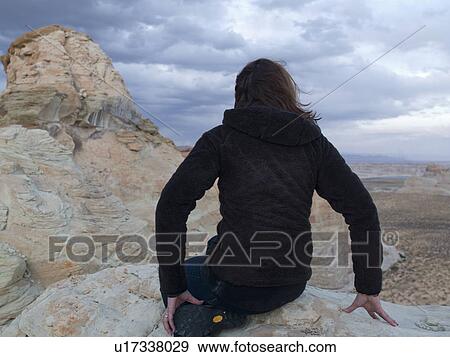 Stock Photo - Woman leaning on rock looking at a view, Utah, USA. Fotosearch