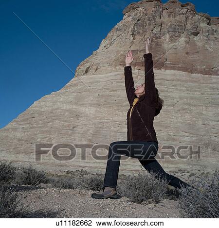 Stock Image - Woman practicing yoga on a rock, Utah, USA. Fotosearch