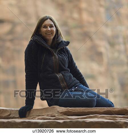 Woman sitting on a rock and smiling, Zion National Park, Utah, USA View Large Photo Image Stock Photograph - Woman sitting on a rock and smiling, Zion National Park, Utah, USA. Fotosearch