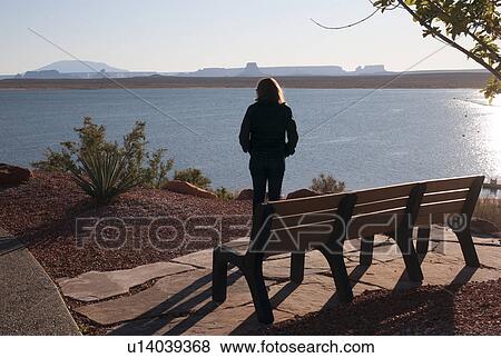 Stock Photo - Woman standing at the lakeside, Lake Powell, Glen Canyon National Recreation Area, Arizona-Utah, USA. Fotosearch