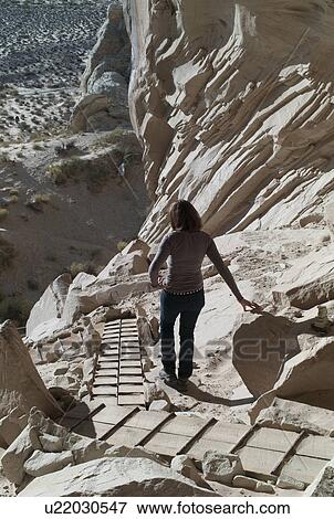 Stock Photo - Woman standing near cliffs, Ulrike's Cave, Amangiri, Utah, USA. Fotosearch