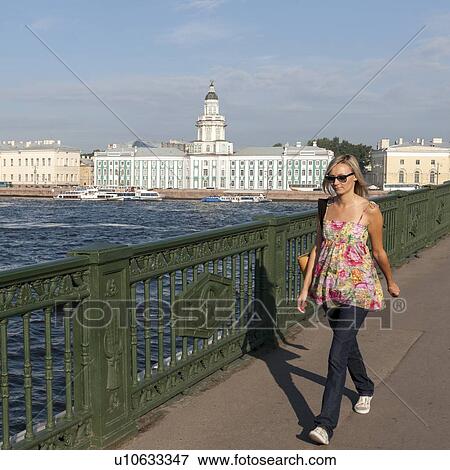 Woman walking on a promenade with a museum in the background, Kunstkamera, Universitetskaya Embankment, Neva River, St. Petersburg, Russia View Large Photo Image Stock Photo - Woman walking on a promenade with a museum in the background, Kunstkamera, Universitetskaya Embankment, Neva River, St. Petersburg, Russia. Fotosearch