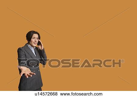Annoyed woman talking on mobile phone with hand outstretched View Large Photo Image Stock Photo - Annoyed woman talking on mobile phone with hand outstretched. Fotosearch