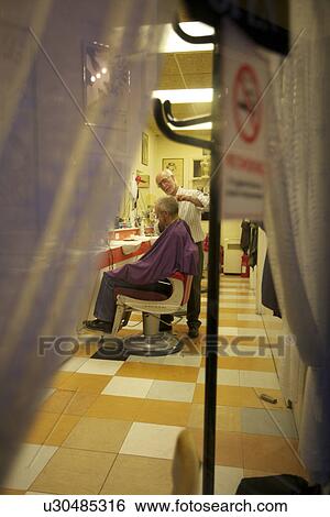 Barber giving a haircut to senior man in salon View Large Photo Image Stock Photograph - Barber giving a haircut to senior man in salon. Fotosearch