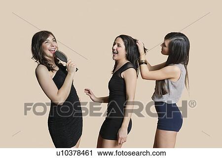 Stock Image - Cheerful young females enjoying together over colored background. Fotosearch