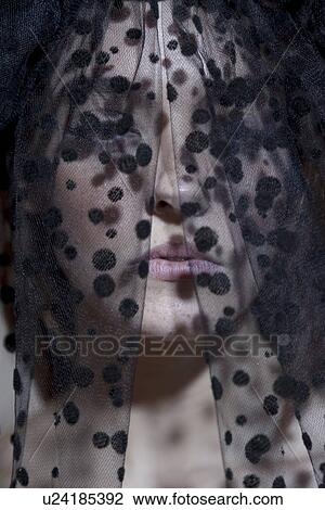 Stock Image - Close-up of a young woman in black veil looking away. Fotosearch