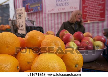 Stock Image - Close-up of fresh orange with apple stack in market. Fotosearch