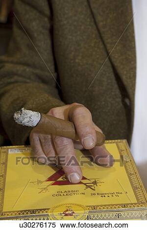 Stock Photography - Cropped image of hands holding burning cigar. Fotosearch