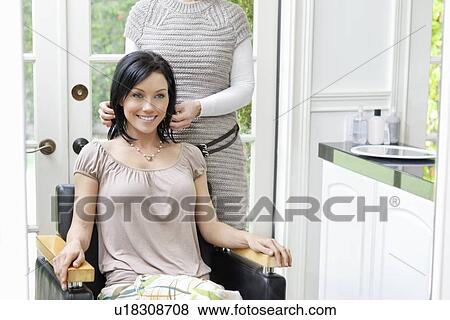 Stock Photo - Happy beautiful mid adult woman with hairstylist in background. Fotosearch