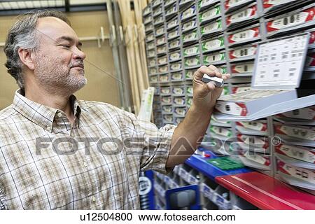 Happy mature man looking at staple pack in store View Large Photo Image Stock Image - Happy mature man looking at staple pack in store. Fotosearch