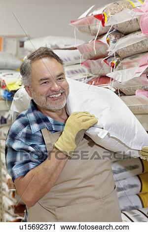 Happy mature salesperson carrying sack in feed store View Large Photo Image Stock Image - Happy mature salesperson carrying sack in feed store. Fotosearch