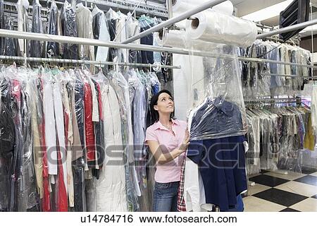 Happy mid adult woman looking up while putting clothes in plastic View Large Photo Image Stock Photograph - Happy mid adult woman looking up while putting clothes in plastic. Fotosearch
