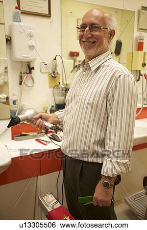 Happy senior man holding hair dryer while looking away in barbershop View Large Photo Image Stock Photograph - Happy senior man holding hair dryer while looking away in barbershop. Fotosearch