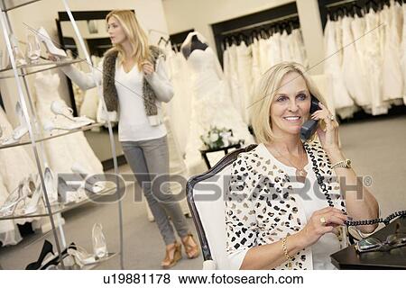 Happy senior woman making a call with daughter in background View Large Photo Image Stock Photo - Happy senior woman making a call with daughter in background. Fotosearch