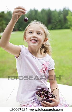 Happy young girl holding bowl full of bing cherries in park View Large Photo Image Picture - Happy young girl holding bowl full of bing cherries in park. Fotosearch