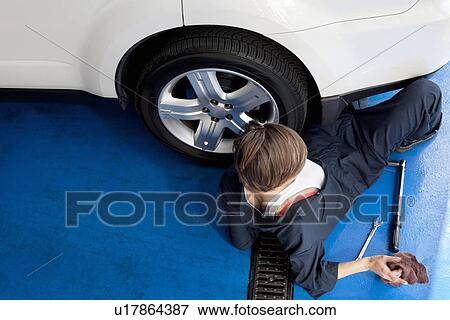 High angle view of woman lying on floor working on car in workshop View Large Photo Image Stock Photo - High angle view of woman lying on floor working on car in workshop. Fotosearch