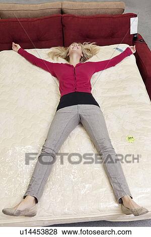 High angle view of woman lying on mattress in furniture store View Large Photo Image Stock Photo - High angle view of woman lying on mattress in furniture store. Fotosearch