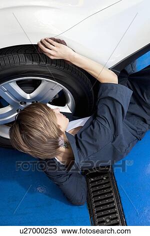 High angle view of young mechanic lying on floor working on car tire in garage View Large Photo Image Stock Image - High angle view of young mechanic lying on floor working on car tire in garage. Fotosearch