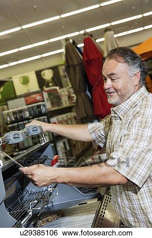 Mature man looking at price tag of machinery in hardware store View Large Photo Image Stock Photograph - Mature man looking at price tag of machinery in hardware store. Fotosearch