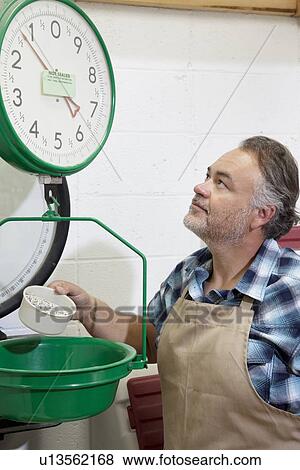 Stock Photo - Mature man looking up at weight scale. Fotosearch