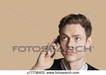 Mid adult man listening to mobile phone over colored background View Large Photo Image Stock Image - Mid adult man listening to mobile phone over colored background. Fotosearch