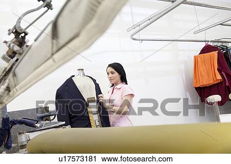 Stock Image - Mid adult woman dressing up mannequin. Fotosearch