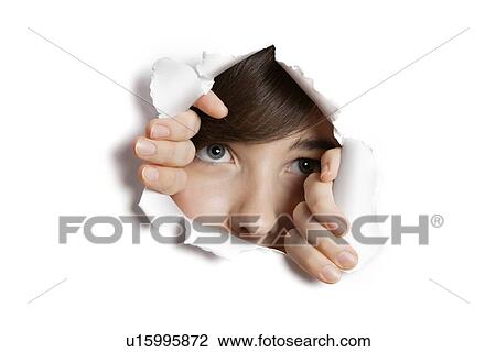 Stock Image - Middle eastern woman peeking from ripped white paper hole. Fotosearch