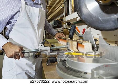 Stock Image - Midsection of young craftsman cutting wood with circular saw. Fotosearch