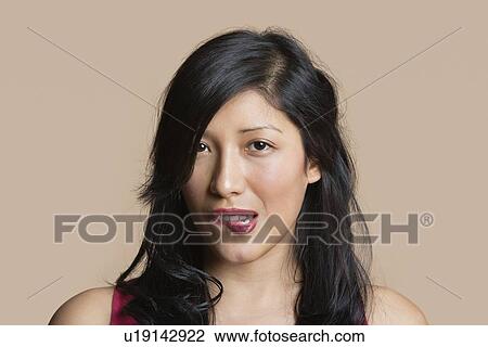 Portrait of a beautiful young woman biting lip over colored background View Large Photo Image Stock Image - Portrait of a beautiful young woman biting lip over colored background. Fotosearch