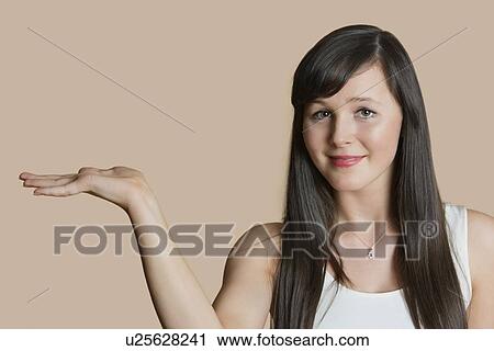 Portrait of a beautiful young woman with empty hand over colored background View Large Photo Image Stock Image - Portrait of a beautiful young woman with empty hand over colored background. Fotosearch