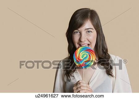 Portrait of a beautiful young woman with lollipop over colored background View Large Photo Image Stock Photo - Portrait of a beautiful young woman with lollipop over colored background. Fotosearch