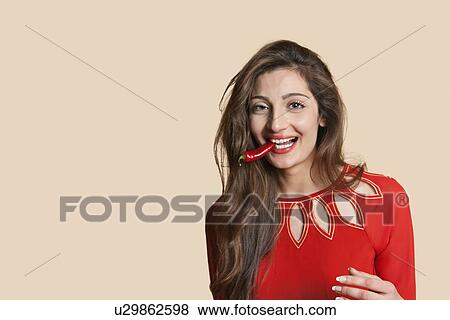 Portrait of a beautiful young woman with red chili pepper in mouth over colored background View Large Photo Image Stock Photo - Portrait of a beautiful young woman with red chili pepper in mouth over colored background. Fotosearch