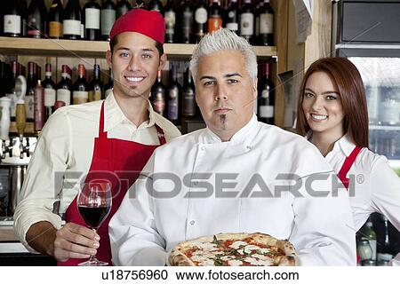 Portrait of a confident chef holding pizza with wait staff in background View Large Photo Image Stock Image - Portrait of a confident chef holding pizza with wait staff in background. Fotosearch