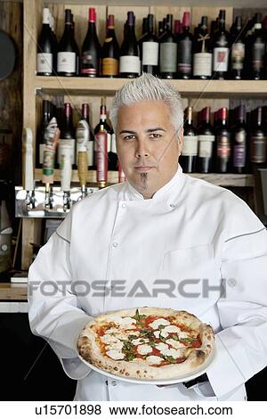 Stock Photo - Portrait of a confident chef with pizza. Fotosearch