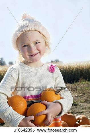 Stock Photography - Portrait of a girl holding pumpkins. Fotosearch