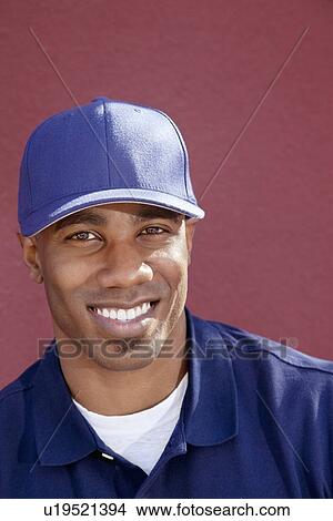 Picture - Portrait of a happy African American man with cap over colored background. Fotosearch
