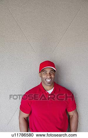 Portrait of a happy African American delivery man against wall View Large Photo Image Stock Image - Portrait of a happy African American delivery man against wall. Fotosearch