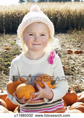 Portrait of a happy girl holding pumpkins in farm View Large Photo Image Stock Image - Portrait of a happy girl holding pumpkins in farm. Fotosearch