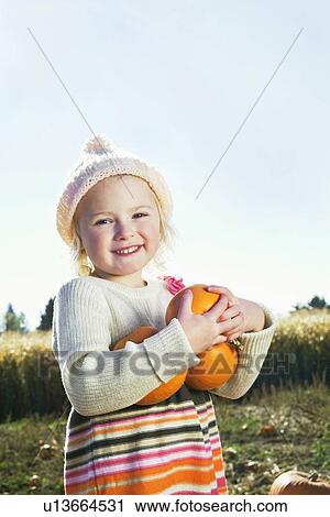Portrait of a happy girl holding pumpkins View Large Photo Image Stock Image - Portrait of a happy girl holding pumpkins. Fotosearch