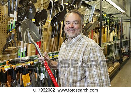 Portrait of a happy mature man holding shovel in hardware store View Large Photo Image Stock Image - Portrait of a happy mature man holding shovel in hardware store. Fotosearch