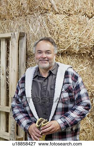 Stock Photo - Portrait of a happy mature man in front of hay stack. Fotosearch