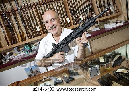 Portrait of a happy mature merchant with rifle in gun shop View Large Photo Image Stock Image - Portrait of a happy mature merchant with rifle in gun shop. Fotosearch