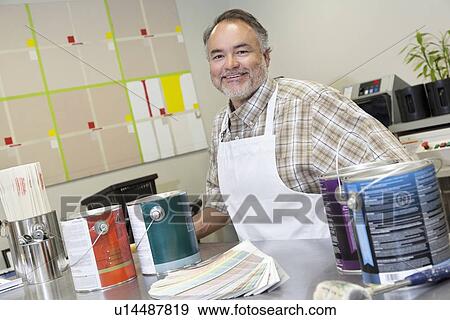 Portrait of a happy mature sales clerk at counter with paint cans in hardware store View Large Photo Image Stock Photo - Portrait of a happy mature sales clerk at counter with paint cans in hardware store. Fotosearch