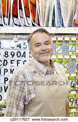 Stock Photo - Portrait of a happy mature salesperson in hardware store. Fotosearch