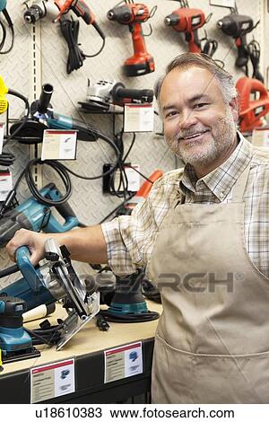 Portrait of a happy salesperson with electric saw in hardware store View Large Photo Image Stock Image - Portrait of a happy salesperson with electric saw in hardware store. Fotosearch